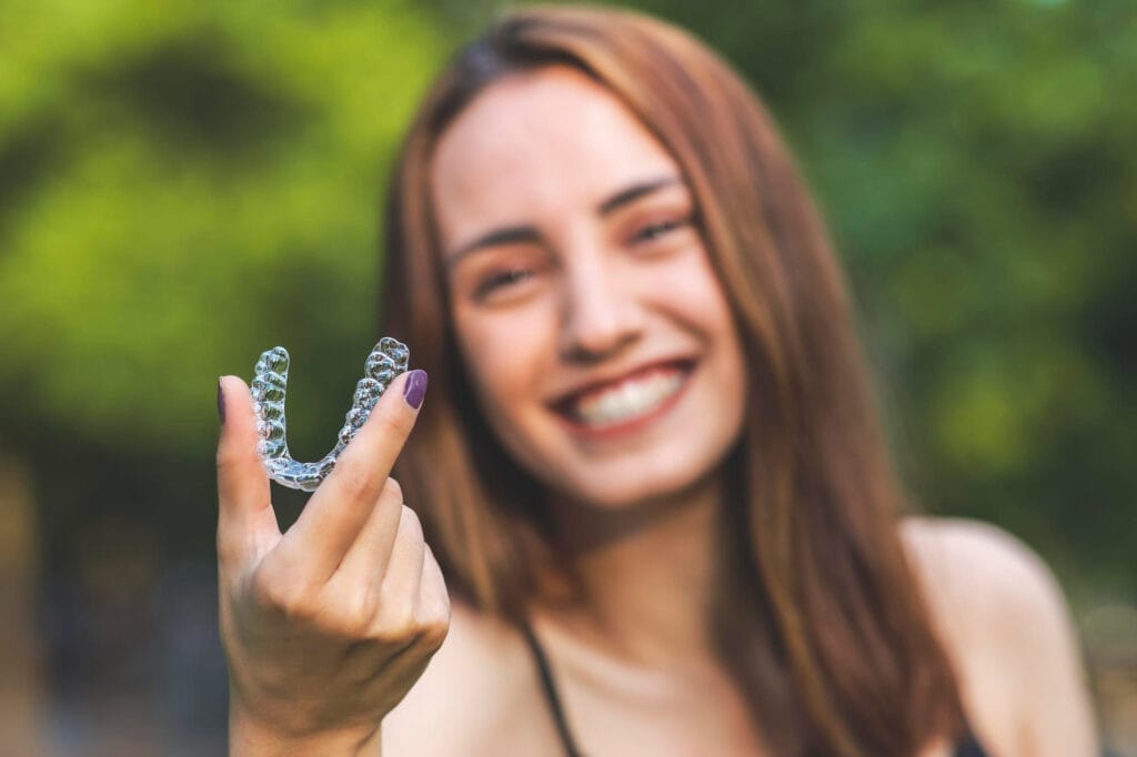 beautiful-smiling-turkish-woman-is-holding-invisalign-bracer-with-vibrant-colors
